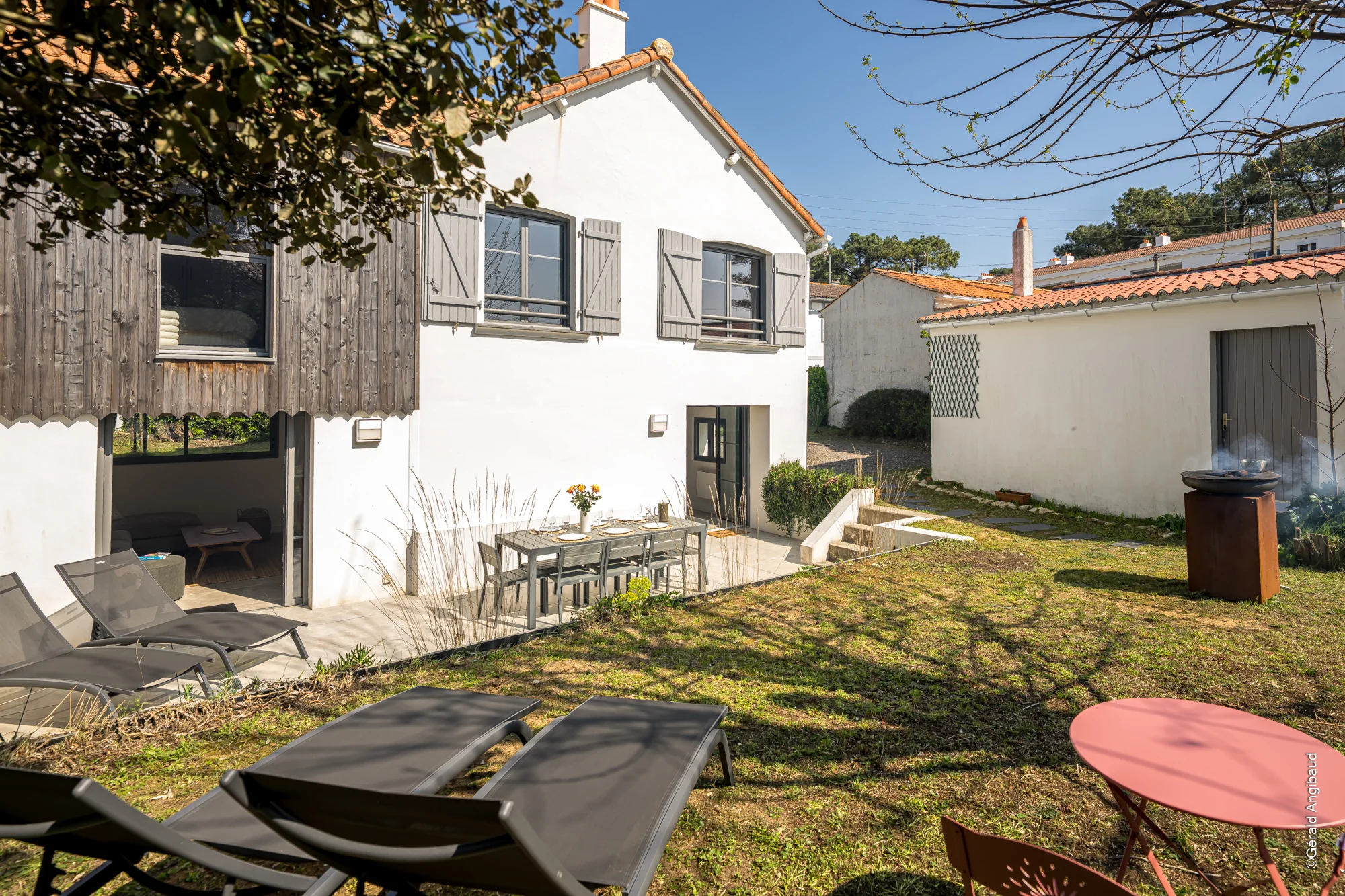 Jardin paysager avec terrasse en bois et transats de standing